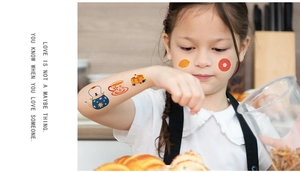 Child wearing colorful cartoon afternoon tea tattoos including tea pot and strawberry cake