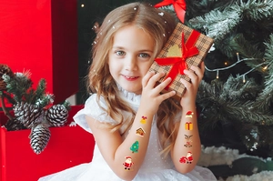 Detailed view of festive Christmas temporary tattoos on a smiling young girl arms