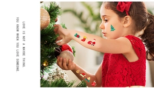 Close-up of a child wearing colorful Christmas cartoon temporary tattoos during a holiday party
