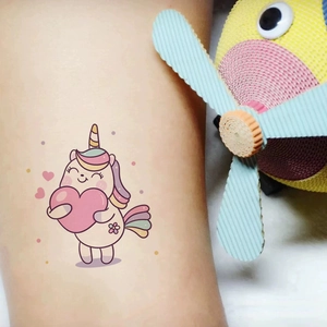 Cute cartoon unicorn tattoo sticker with pink heart and rainbow mane on child's arm