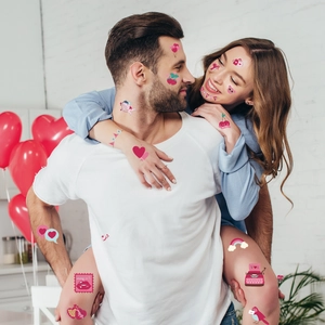 Valentine temporary tattoos featuring heart and cupid designs on model face and arms