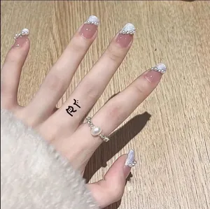 Détail de faux ongles roses avec fleurs blanches en relief et accents de perles