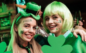 Women wearing Saint Patrick's Day shamrock tattoos, green bob wig and mini top hat