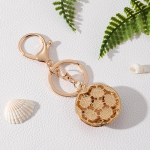 Golden alloy rhinestone football keychain with lobster clasp on white textured background