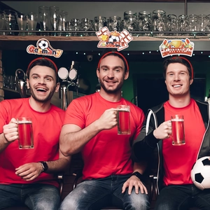 Three fans wearing soccer themed party boppers with Germany and Winner motifs in a bar