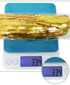Macro view of a 30g gold metallic cheerleading pom pom being weighed on a scale