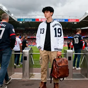 Veste de baseball bleue et blanche numéro 13 avec pantalon cargo kaki sur un terrain de foot