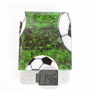 Detailed view of the soccer themed plastic tablecloth weighing 114.6g on a digital scale