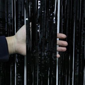 Detail of glossy black foil fringe curtain showing material texture and light density