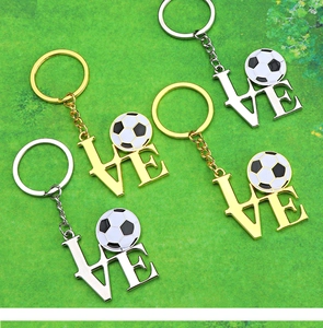 Polished metal LOVE football keychains in gold and silver on green turf background