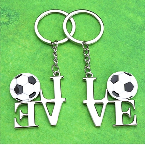 Detailed view of silver alloy puzzle keychain with soccer ball pattern on green grass background