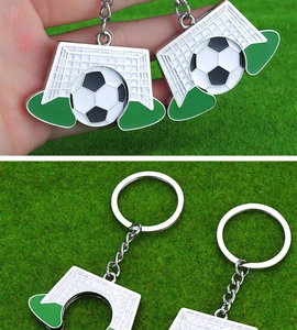 Detailed close-up of a metal football and goal keychain on a green grass background