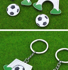 Close-up of metal football keychain with goal charm on synthetic grass background