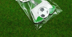 Close-up of a 2026 World Cup style metal football keychain with green turf background