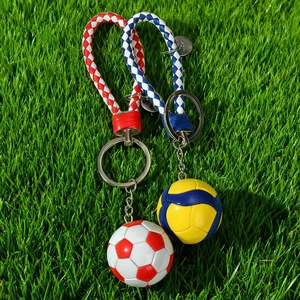 Soccer and volleyball keychains with woven lanyards on green grass background