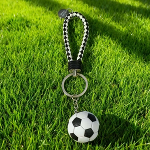 Detail of soccer ball keychain with black and white woven strap on green grass