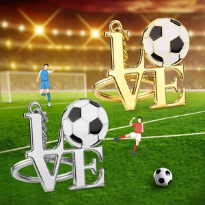 Gold and silver metal LOVE football keychains with enamel soccer balls on a grass field