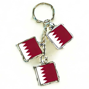 Detail of three rectangular Qatar flag pendants with silver metal keychains on a white background