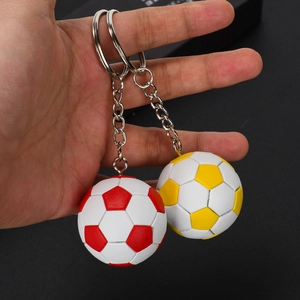 Close-up of red and yellow mini soccer ball keychains held in hand with metal rings