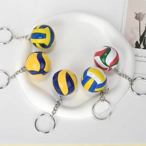Five assorted miniature volleyball keychains on a ceramic tray with a modern design
