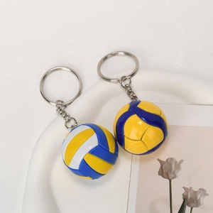 Blue and yellow 3D volleyball keychain with metallic ring on a minimalist white tray