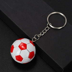 Close-up of a glossy red and white soccer ball keychain resting on a black gift box