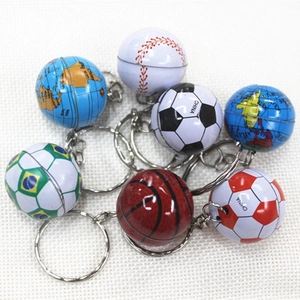 Close-up of assorted mini football, basketball, baseball, and globe metal keychains on cloth