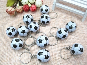 Detailed cluster of mini black and white football keychains on a rustic linen fabric surface