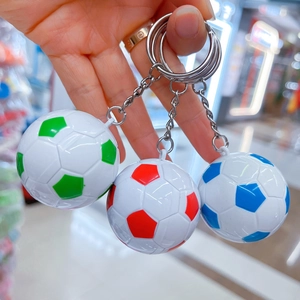 Primo piano di portachiavi a forma di mini pallone da calcio rosso, verde e blu in mano