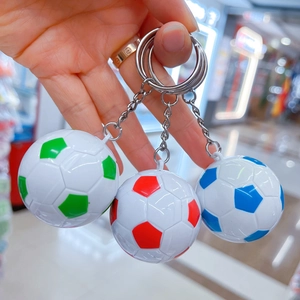 Mano che tiene tre mini portachiavi a forma di pallone da calcio in rosso, verde e blu