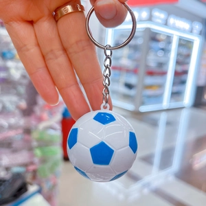 Primo piano di un portachiavi da calcio blu e bianco con anello in metallo tenuto in mano