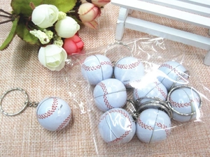 Close-up of mini baseball keychains with red stitching on a rustic linen background
