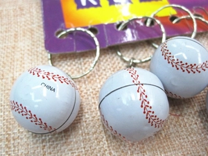 Detail of white metal baseball keychains with red stitching and silver rings on display cards