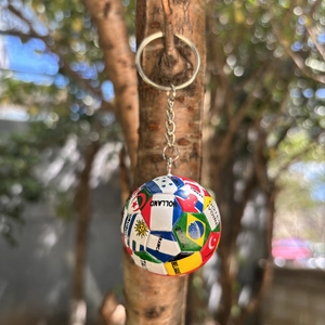 Detail eines Weltflaggen-Fußballschlüsselanhängers an einem Ast mit Bokeh-Hintergrund