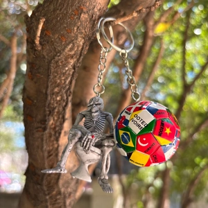 Detail von Fußball-Schlüsselanhänger mit Flaggen und Totenkopf-Anhänger an Baumrinde