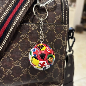 Detail eines Fußball-Schlüsselanhängers mit Nationalflaggen an einer braunen Handtasche