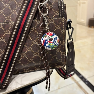 Detailaufnahme eines Fußball-Schlüsselanhängers mit Nationalflaggen an einer Handtasche