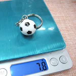 Dettaglio di un mini portachiavi a pallone da calcio su una bilancia che pesa 7,8g