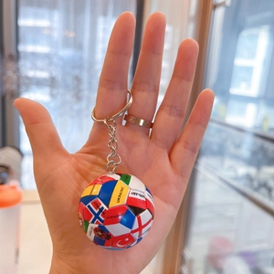 Detail eines Miniatur-Fußball-Schlüsselanhängers mit Flaggen und Metallkette in der Hand
