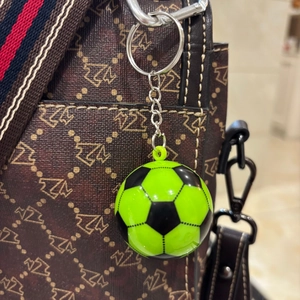 Dettaglio portachiavi a pallone da calcio verde neon su una borsa marrone con fantasia