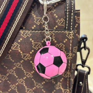 Dettaglio di un portachiavi a forma di pallone rosa e nero con catena in metallo