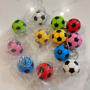 Dettaglio di portachiavi a forma di pallone da calcio in vari colori su base marmo