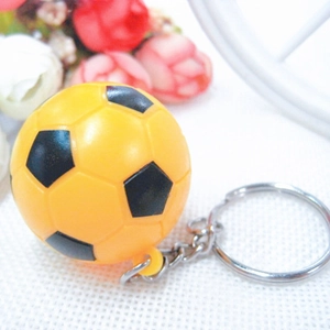 Miniature yellow and black football keychain with silver metal ring on floral background