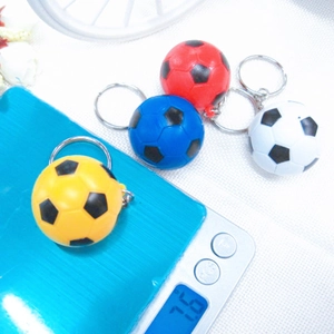 Close-up of a 7.6g mini soccer keychain on an electronic scale showing weight