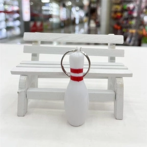 Close-up of a white plastic bowling pin keychain with red stripes and metal ring