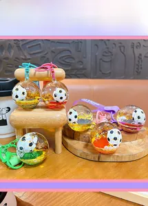 Close-up of a liquid quicksand soccer keychain with purple strap on a wooden tray