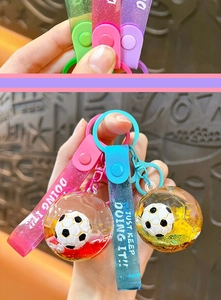 Detail view of soccer-shaped liquid quicksand keychain with motivational PVC strap
