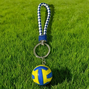 Blue and yellow volleyball keychain charm with braided strap on a green grass field