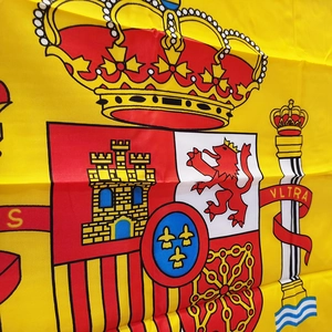 Close-up of the Spanish flag coat of arms showing detailed embroidery and crown on yellow polyester