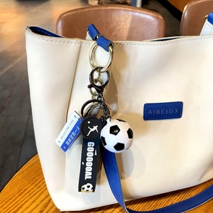 Detail of football keychain with goal pendant on blue and white leather bag